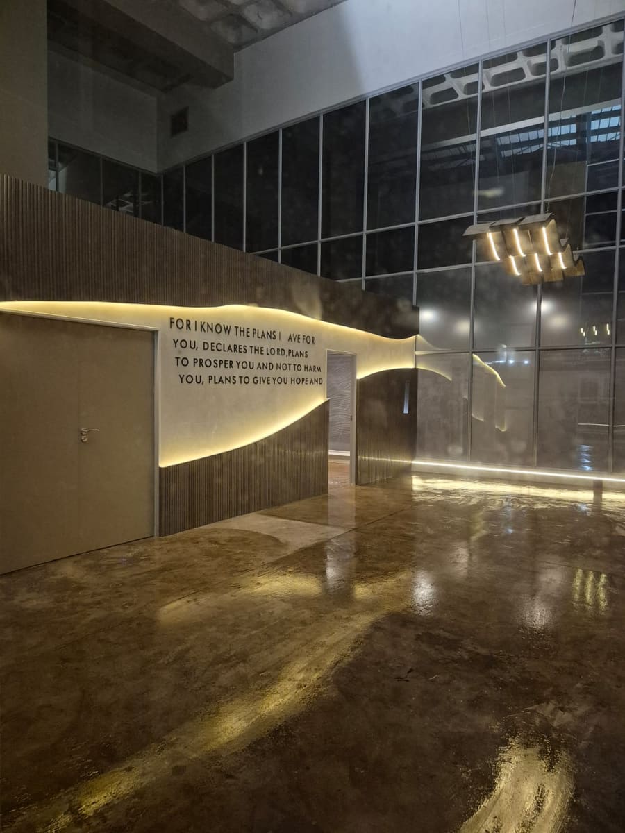 The feature wall lit after dark, the concealed light washing down onto a polished floor.