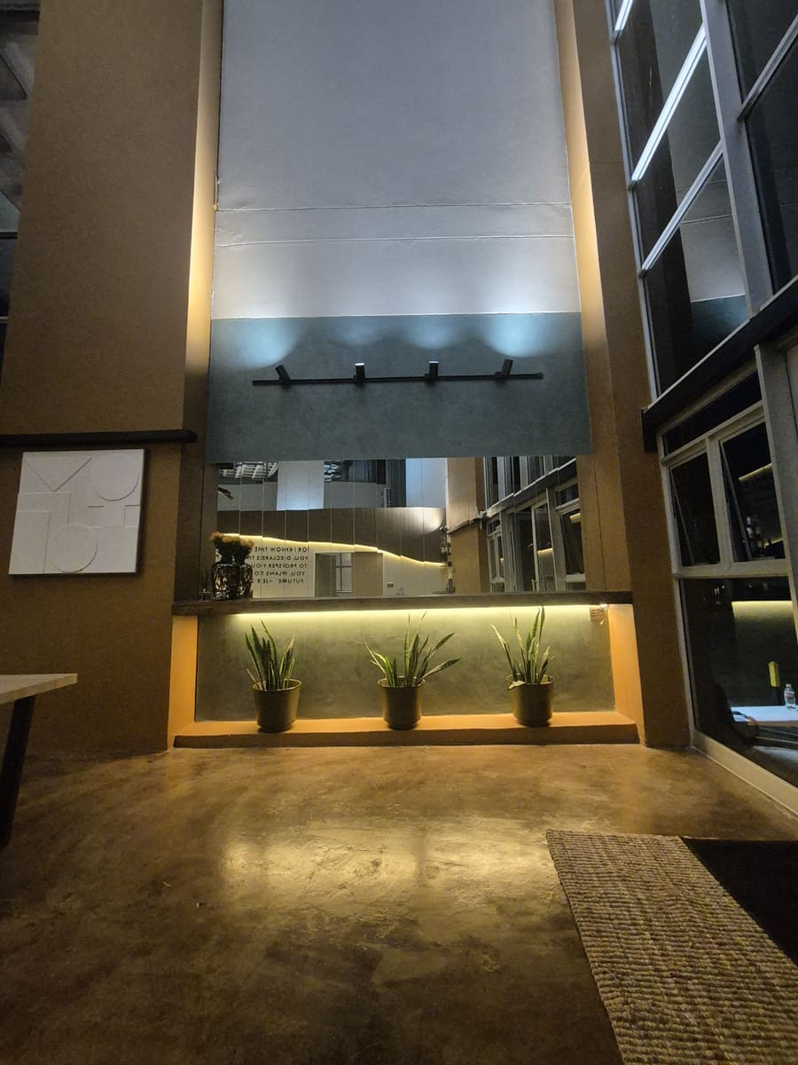 A planted timber ledge lit from beneath, against the dark panelled entrance wall.