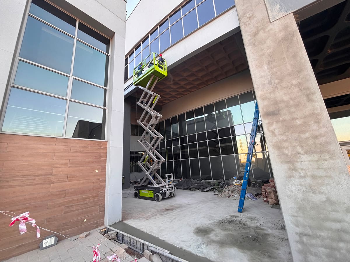 A scissor lift at the facade, with the concrete column and soffit above.